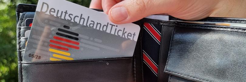 Eine Hand zieht ein Deutschlandticket aus einem Portmonee