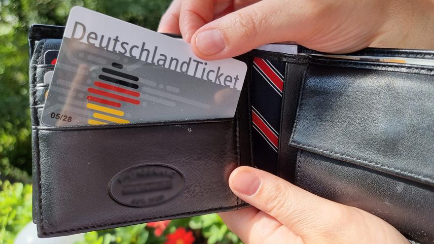 Eine Hand zieht ein Deutschlandticket aus einem Portmonee